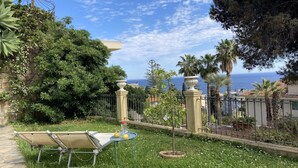 A garden with a sun lounger, a small table with lemons, and a view of the sea. - Sanremo: Apartment in Provencal villa with garden (Sanremo)