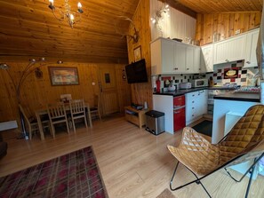 A wooden interior with a dining area, kitchen, and a TV mounted on the wall.