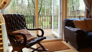 Ein Zimmer mit Schaukelstuhl, einer Couch und einer Glastür zu einer Terrasse mit Holzgeländer.
