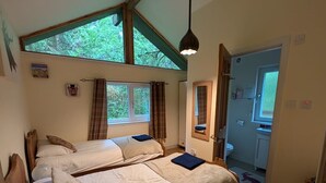 Ein Schlafzimmer mit zwei Betten, einem Oberlicht, einem Deckenventilator und Blick ins Freie.