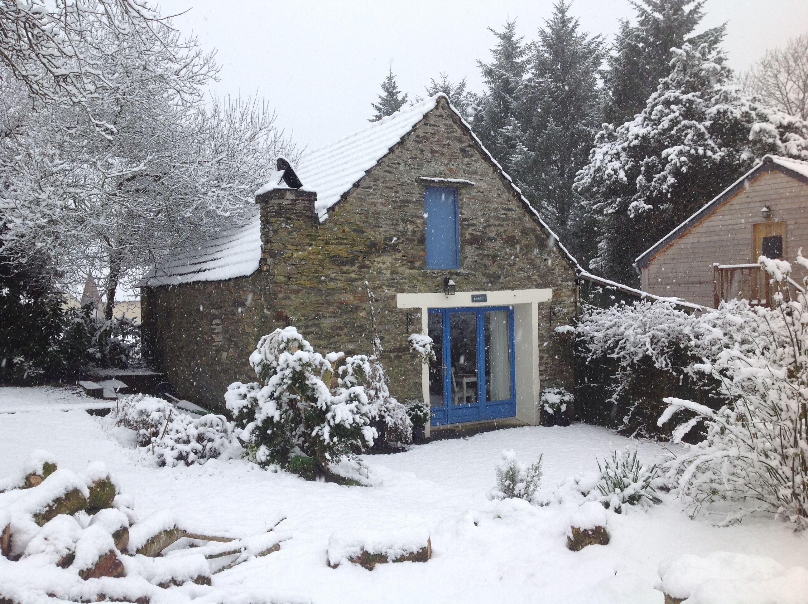 A stone building with a blue door and a chimney.