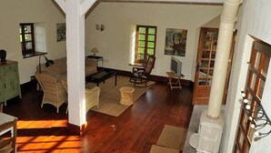 A spacious living area with wooden flooring, a fireplace, and a dining area with wicker furniture.