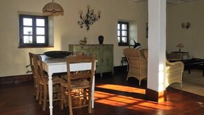 A dining area with a wooden table and chairs, a green cabinet, and a chandelier.