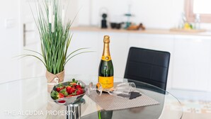 Een glazen tafel met een champagnefles, een schaal aardbeien en een potplant.