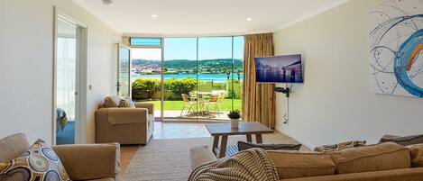 A modern living room with a large sliding glass door leading to a balcony with a scenic view.