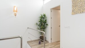 Eine moderne Treppe mit Metallgeländer, einem Blumentopf und einer Wandleuchte.
