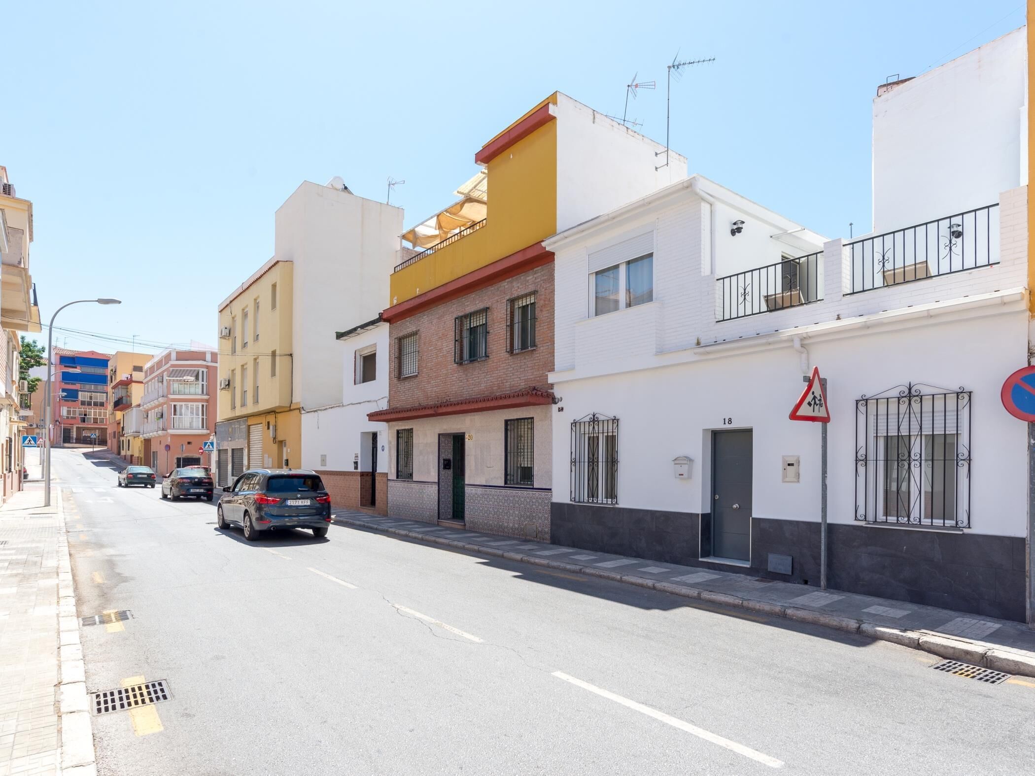 Une rue bordée d’immeubles à plusieurs étages, avec un panneau indiquant l’interdiction de se garer et un passage piéton.