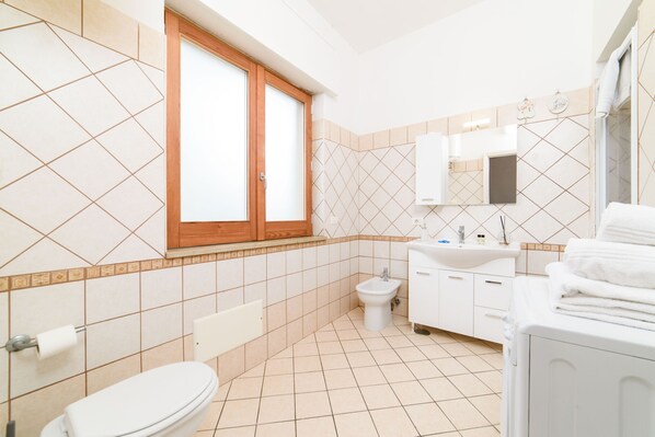 A modern bathroom with a toilet, bidet, sink, and stacked towels. - Casa Laura Blu (Sant´Agnello)