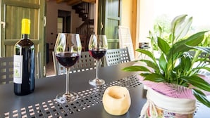 Een tafel met een fles wijn, twee rode wijnglazen, een klein schaaltje en een potplant.
