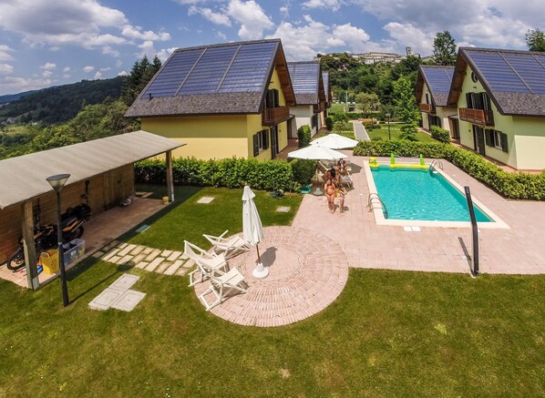 A residential area with two houses, a swimming pool, and a covered patio area.