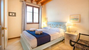 A bedroom with a bed, bedside table, lamp, and a chair.