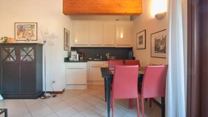 A kitchen with white cabinets, a dining table with red chairs, and a wooden ceiling.