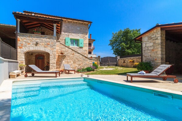 A stone building with a swimming pool, two lounge chairs, and a small garden. - Charming stone house with private pool and garden (Glavani, Barban)