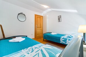 A bedroom with two beds, a wooden door, a mirror, and a lamp. - Charming stone house with private pool and garden (Glavani, Barban)
