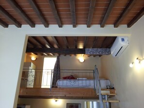 A loft bedroom with a bunk bed, wooden beams, an air conditioning unit, and a staircase. - Residence MONNA LISA accommodates up to 7 people (Firenze)