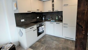A modern kitchen with white cabinets, a dark countertop, and a built-in oven.