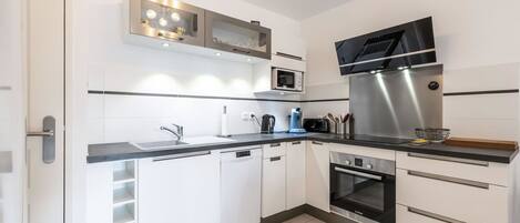 A modern kitchen with white cabinets, a stainless steel range hood, a Bosch oven, and a microwave.
