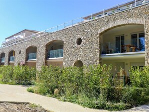 Stunning building with arched windows and balconies, surrounded by lush greenery and a paved pathway.
