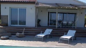Un espace aménagé au bord de la piscine, avec des chaises longues et un patio couvert.