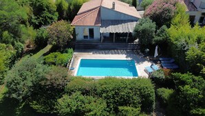 Vue aérienne d’une maison avec une piscine, entourée d’une végétation luxuriante.