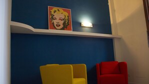 A room with a blue accent wall, a red and yellow chair, and a framed artwork above the chair.