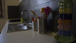 A kitchen counter with a sink, a utensil holder, and stacked plates.