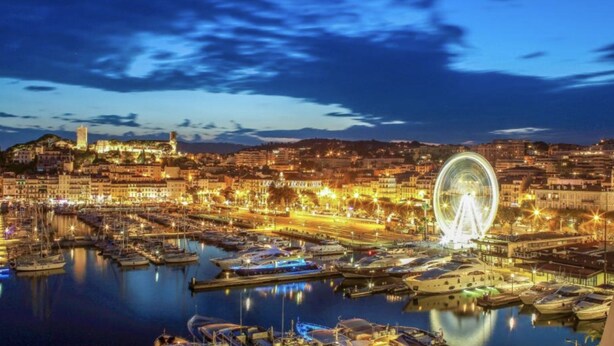 A marina with boats docked, a Ferris wheel, and a cityscape with buildings and a hill in the background. - Cocooning house - sea view - 4km from CANNES - 6 travellers (Golfe-Juan)