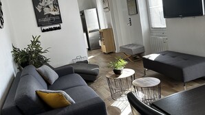 A modern living room with a sectional sofa, a small round table, and a flat-screen TV mounted on the wall. - Cocooning house - sea view - 4km from CANNES - 6 travellers (Golfe-Juan)