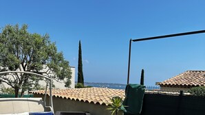 An outdoor patio with a long dining table, wicker furniture, and a view of the sea. - Cocooning house - sea view - 4km from CANNES - 6 travellers (Golfe-Juan)