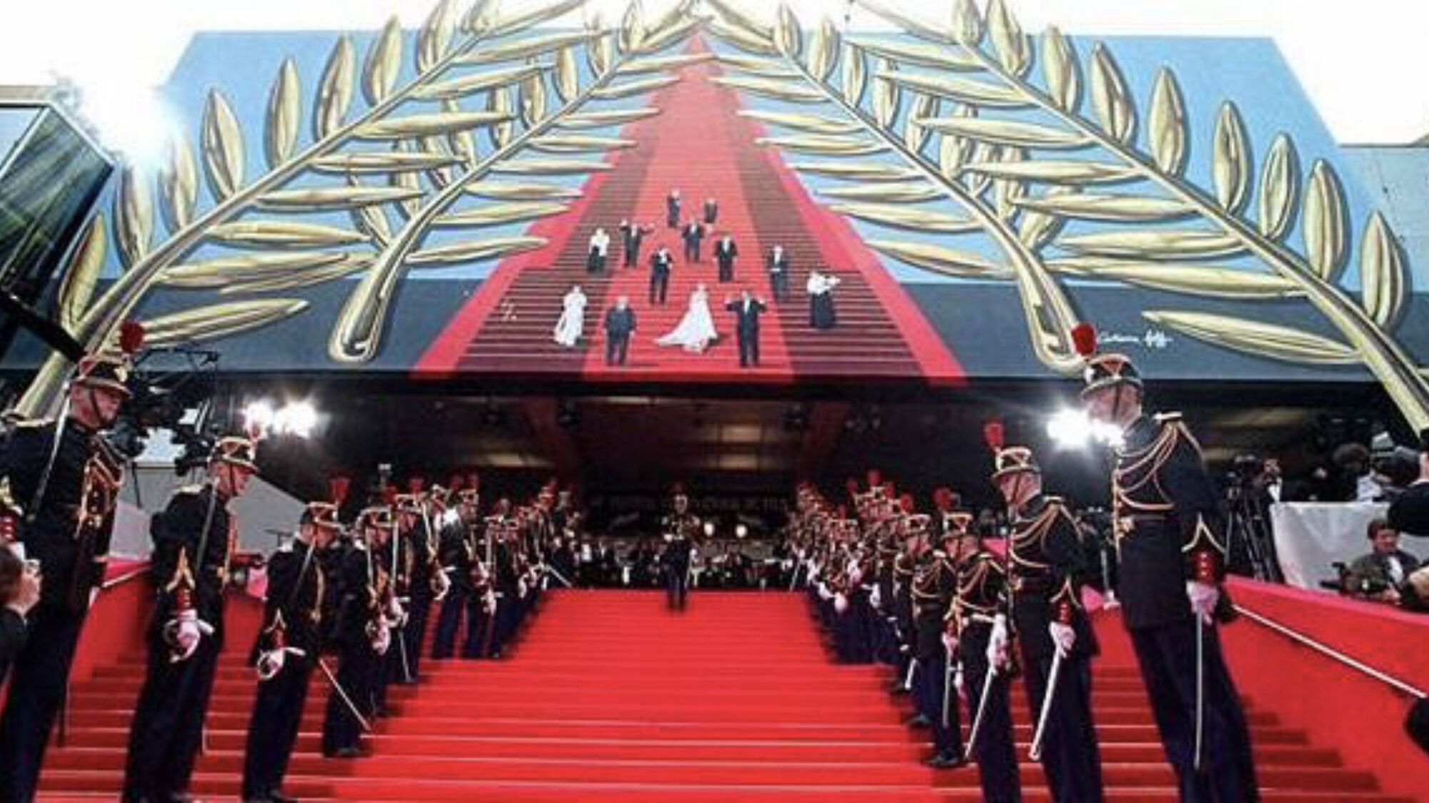 Un grand escalier recouvert d’un tapis rouge mène à l’entrée d’un bâtiment, de part et d’autre duquel se tiennent des gardes en uniforme.