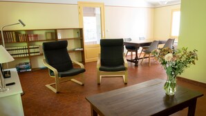 A room with two armchairs, a wooden table, a bookshelf, and a dining table with chairs. - Flat with loggia in a charming 18th century family estate, quiet, with independant entrance. (Hyères)