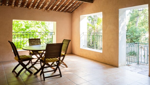A covered patio with a table and chairs, large windows, and a wooden ceiling. - Flat with loggia in a charming 18th century family estate, quiet, with independant entrance. (Hyères)