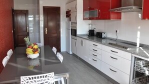 A modern kitchen with white cabinets, a red backsplash, and a dining table with chairs. - Villa 500 meters from the sea with private saltwater pool in Meia Praia (Lagos)