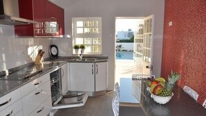 A modern kitchen with white cabinets, a granite countertop, and a view of a swimming pool through a glass door. - Villa 500 meters from the sea with private saltwater pool in Meia Praia (Lagos)