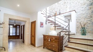 Ein Flur mit Treppe, Holztüren, einem Schmuckkästchen und einer Steinwand.