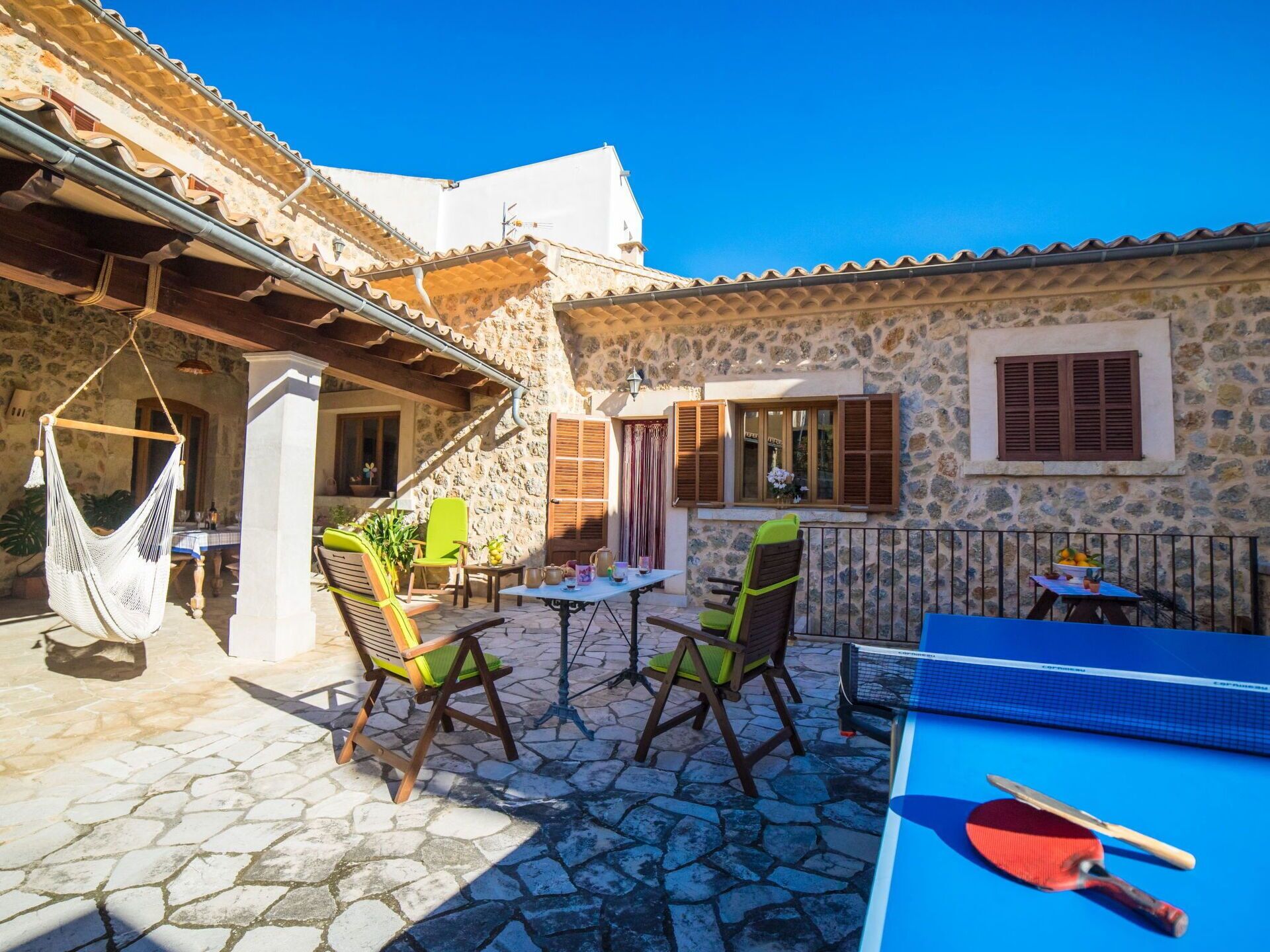 Un patio con paredes de piedra, mobiliario exterior y una mesa de ping pong.