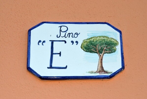 A ceramic sign with the inscription "Pino E" and an illustration of a tree.