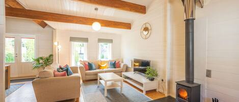 A cozy living room with a fireplace, wooden beams, a sofa, and a television.