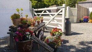 A garden gate with potted plants and a wooden sign.