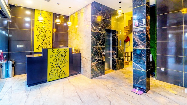 A modern reception area with marble walls, a black reception desk, and yellow decorative panels. - Hotel City Castle Prime (Amritsar)