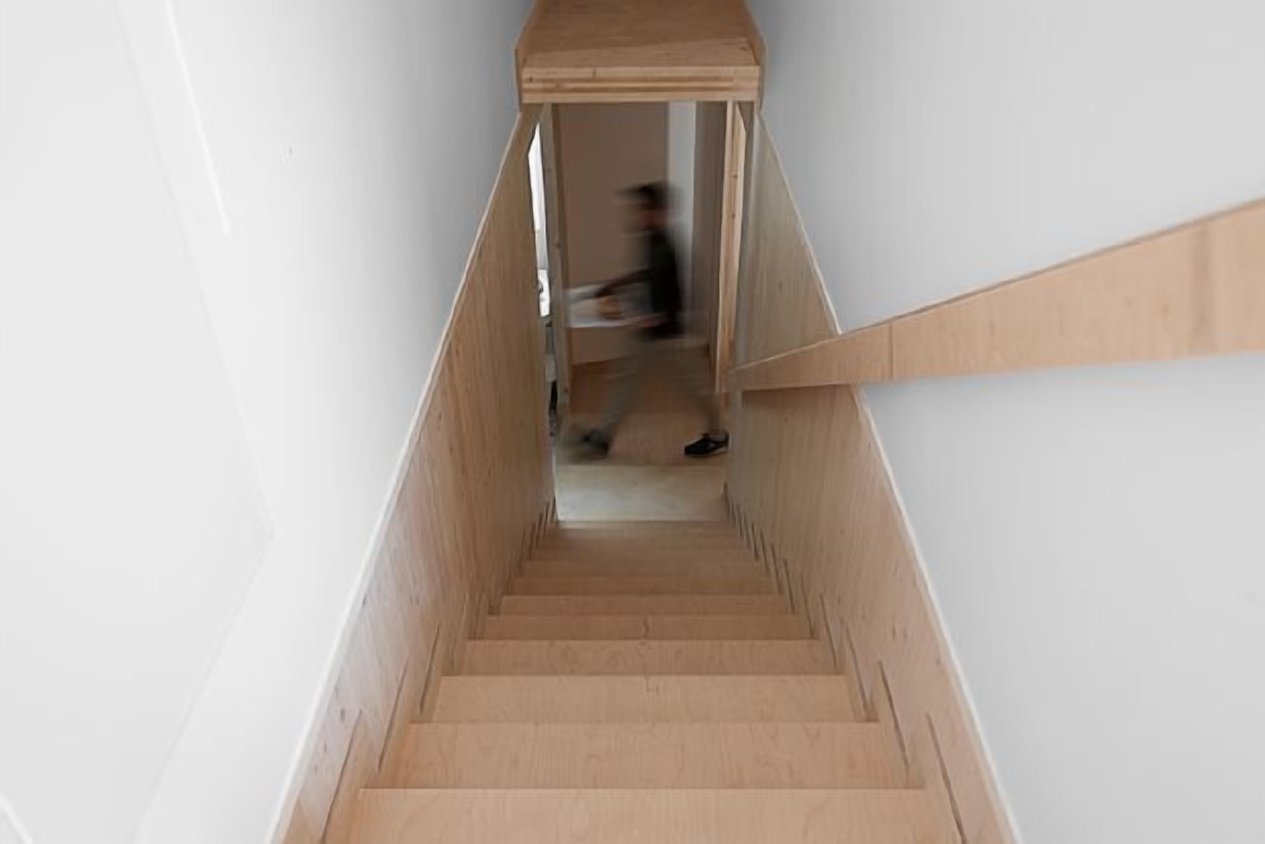 Una escalera de madera estrecha de diseño sencillo que conduce a una plataforma.