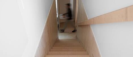 Una escalera de madera estrecha de diseño sencillo que conduce a una plataforma.