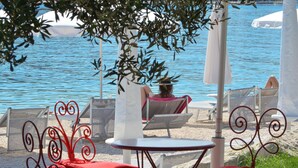 Un espace de détente aménagé sur la plage, avec des chaises et des tables, donnant sur une étendue d’eau.
