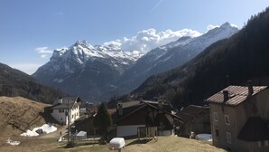 Ein Bergdorf mit traditionellen Häusern, einem klaren Himmel und einem schneebedeckten Gipfel im Hintergrund.