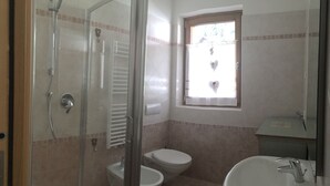 Ein Badezimmer mit Duschkabine, Toilette, Bidet und Waschbecken.