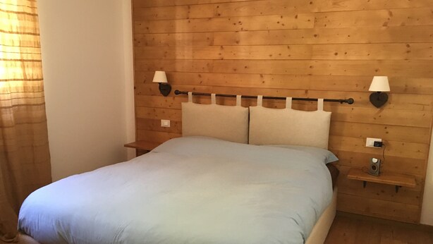 Ein Schlafzimmer mit einem hölzernen Kopfteil, einem Bett mit einer hellblauen Bettdecke, zwei Nachttischlampen und einem kleinen Nachttisch mit einer Lampe.