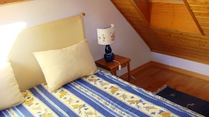 Une chambre à coucher avec un lit, des oreillers, une lampe et des poutres en bois au plafond.