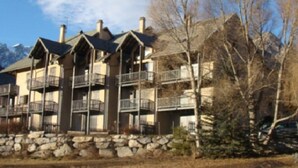 Un hôtel à plusieurs étages, doté de balcons, d’une fondation en pierre et situé dans un cadre montagneux.