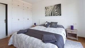 A bedroom with a large bed, a wardrobe, a nightstand, and a zebra print artwork on the wall. - 3 Bedroom Villa, private pool,  stunning Sea Views 5 mins from beach. WIFI & AC (Arenal D'en Castell)