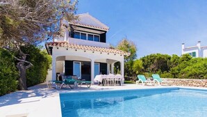 A two-story house with a swimming pool, outdoor furniture, and a garden. - 3 Bedroom Villa, private pool,  stunning Sea Views 5 mins from beach. WIFI & AC (Arenal D'en Castell)